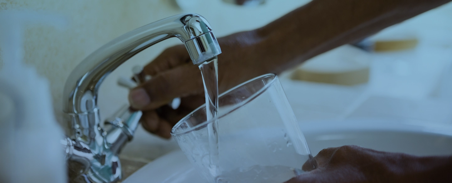 pouring water on a glass from a faucet